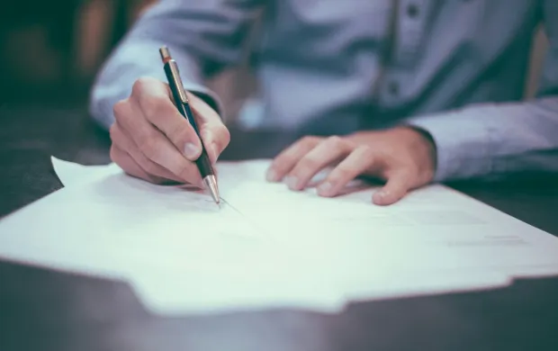 Documents and a pen arranged on a wood table
