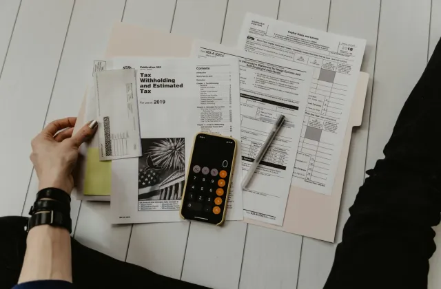 Hands reviewing tax documents with a calculator and pen